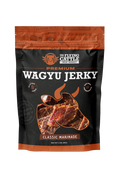 A 3 oz bag of The Flying Cattle Premium Wagyu Jerky in Classic Marinade, featuring a black and orange design with a graphic of marinated beef slices.